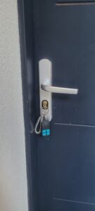Clé grippée dans la serrure : dépannage et déblocage Clé insérée dans le cylindre d’une porte bleu foncé équipée d’une poignée argentée.